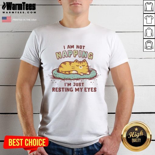 Alt Text: Cute cat t-shirt featuring the phrase I Am Not Napping, I'M Just Resting My Eyes in playful typography.
