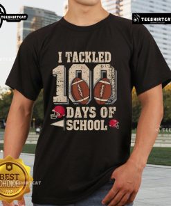 Boy wearing 'Top 100 Days Of School' football t-shirt celebrating 100th day of school with friends in a classroom.