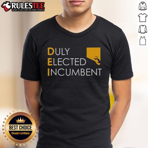 Alt Text: Top M Scott proudly wearing a Dei Duly Elected Incumbent T-shirt at a community event, promoting civic engagement.