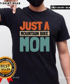 Mountain bike mom wearing a 'Just A Mountain Bike Mom' T-shirt, biking on a scenic trail with vibrant nature.