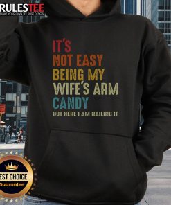 Man wearing 'It's Not Easy Being My Wife's Arm Candy' hoodie, showcasing style and humor in casual fashion.