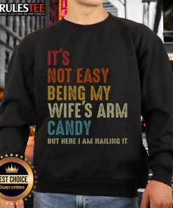 Man wearing 'It's Not Easy Being My Wife's Arm Candy' sweatshirt, showcasing style and humor in casual fashion.