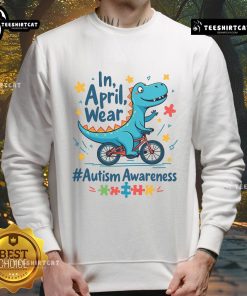 Cute dinosaur in a sweatshirt promoting Autism Awareness for April, showcasing colorful designs and a friendly smile.