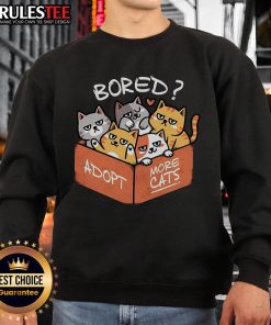 Cute bored cat wearing a sweatshirt that says 'Adopt More Cats' promoting cat adoption and awareness.