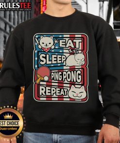 Alt Text: Cute cat in a patriotic sweatshirt playing ping pong, embodying the eat, sleep, table tennis, repeat lifestyle.