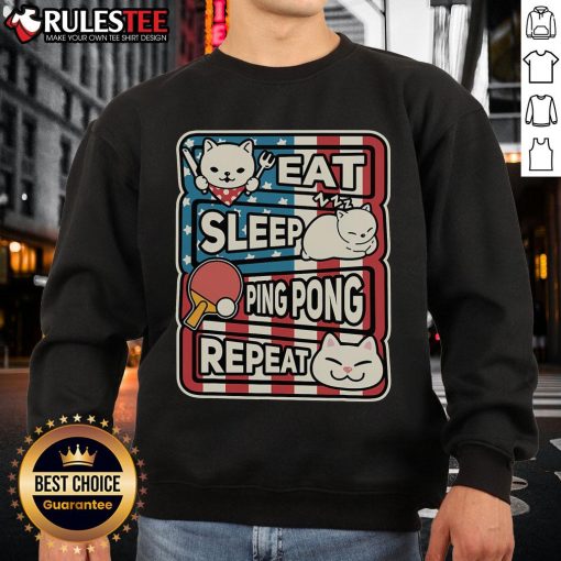 Alt Text: Cute cat in a patriotic sweatshirt playing ping pong, embodying the eat, sleep, table tennis, repeat lifestyle.