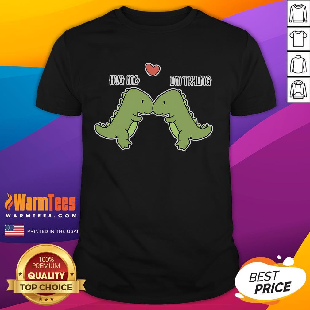 Cute Dinosaur Hug Me I'M Trying Funny T Shirt Alt Text: Cute dinosaur graphic on a funny t-shirt with the phrase Hug Me I'm Trying for a playful and humorous style.