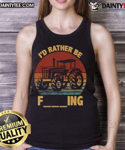 Farmer wearing a tank top with 'Good I'd Rather Be Farming' joke, standing next to a tractor on a sunny day.