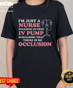 Nurse wearing a 'Good I'm Just A Nurse' tee stands confidently in front of an IV pump, showcasing dedication to healthcare.