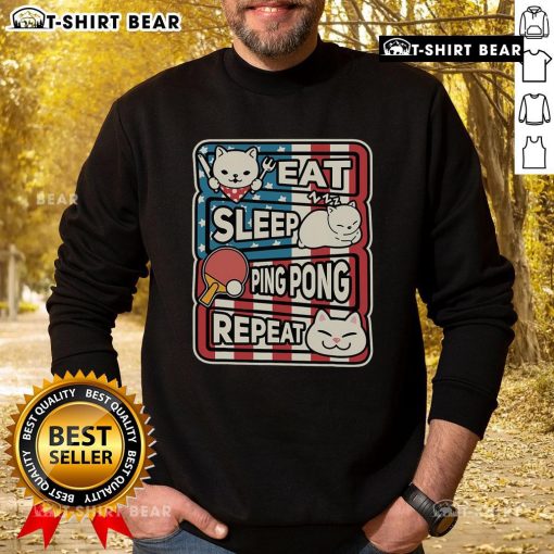 Cute cat in a patriotic sweatshirt playing ping pong, representing the eat, sleep, table tennis, repeat lifestyle.