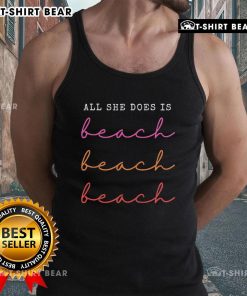Woman wearing 'Top All She Does Is Beach Repeat' tank top at the beach, enjoying the sun and waves.