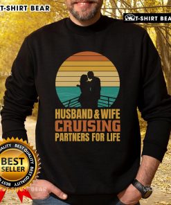 Couple wearing 'Top Husband and Wife Cruising Partners for Life' sweatshirt against a vintage sunset backdrop on a cruise.