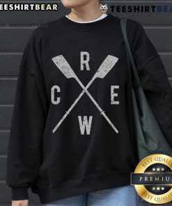Top rowing crew wearing sweatshirts, showcasing crossed oars, teamwork, and dedication in a competitive rowing environment.