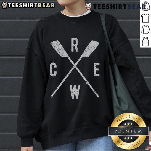 Top rowing crew wearing sweatshirts, showcasing crossed oars, teamwork, and dedication in a competitive rowing environment.