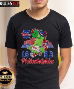 Alt Text: Awesome Phillie Phanatic mascot on 1883 Philadelphia Phillies skyline T-shirt, perfect for baseball fans.