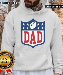 Happy dad wearing an American football hoodie, smiling proudly while holding a football in a sunny park.