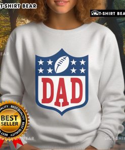 Happy dad wearing an American football sweatshirt, smiling in a park, showcasing team spirit and family fun.