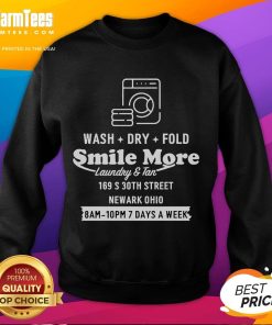 Happy Roman Atwood wearing a 'Smile More' sweatshirt while doing laundry in Newark, Ohio, showcasing his joyful personality.
