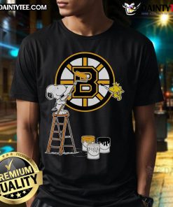 Snoopy and Woodstock painting Boston Bruins logo on a t-shirt, showcasing a fun and vibrant sports design.