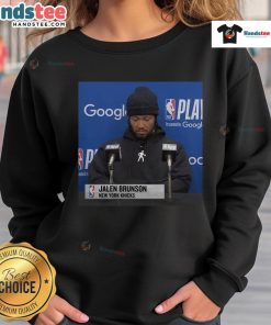 Jalen Brunson at an official press conference wearing a stylish sweatshirt, showcasing his signature style.