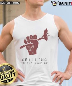 Man wearing a tank top humorously grilling outdoors, showcasing a fun summer vibe and cooking skills.