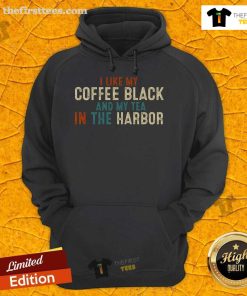 Vintage hoodie reading 'I Like Coffee Black and My Tea in the Harbor' displayed against a cozy cafe backdrop.
