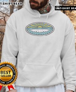 Model wearing a Wituka hoodie on a sunny shore, showcasing beach vibes and stylish outdoor fashion.