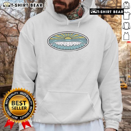 Model wearing a Wituka hoodie on a sunny shore, showcasing beach vibes and stylish outdoor fashion.