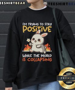Cute bunny on a sweatshirt with the phrase I'm trying to stay positive while the world is collapsing. Perfect for cozy vibes.