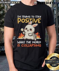 Alt Text: Cute bunny graphic on a t-shirt with the phrase I'M Trying To Stay Positive While The World Is Collapsing.