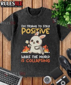 Alt Text: Funny bunny graphic on a washed t-shirt, expressing positivity amidst chaos with the text I'm Trying to Stay Positive.