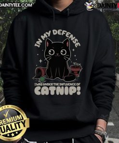 Funny cat in a cozy hoodie, captioned 'In My Defense, I Was Under The Influence of Catnip,' showcasing playful feline humor.