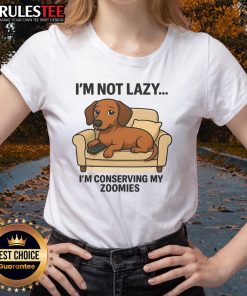 Funny dog lounging with a playful expression, wearing a I'm not lazy, I'm conserving my zoomies tee. Perfect for pet lovers!