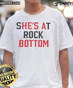 Funny 'She's at Rock Bottom, He's a Bottom' t-shirt design featuring playful text for humor and style.