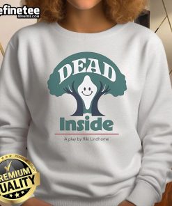 Riki Lindhome wearing a 'Dead Inside' sweatshirt, smiling happily in a scene from the play 'A Play Sweatshirt'.