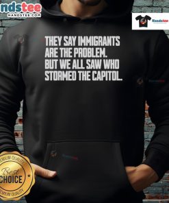 Hot hoodie with text 'They say immigrants are the problem, but we all saw who stormed the Capitol' highlighting immigration issues.