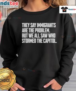 Hot sweatshirt with text 'They Say Immigrants Are The Problem, But We All Saw Who Stormed The Capitol' addressing immigration issues.