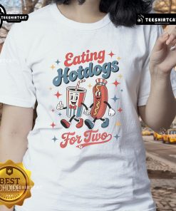 Two ladies enjoying hotdogs at a picnic, wearing the 'Nice Eating Hotdogs' tee, smiling and having a great time outdoors.