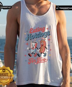 Couple enjoying hot dogs together while wearing a 'Nice Eating Hotdogs For Two' tank top at a sunny outdoor picnic.