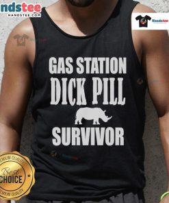 Man wearing a Nice Gas Station Dick Pill Survivor tank top, standing in front of a vintage gas station under bright sunlight.