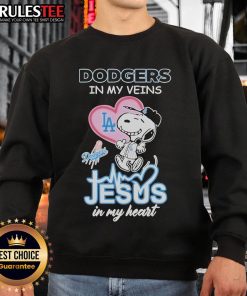 Cozy Snoopy Peanuts sweatshirt featuring 'Los Angeles Dodgers in my veins, Jesus in my heart' design.