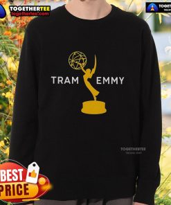 Tramell Tillman wearing an Emmy sweatshirt while posing next to a tram, showcasing his stylish look and personality.