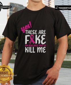 Official Yes These Are Fake My Real One Tried To Kill Me Breast Cancer Awareness T-Shirt featuring bold pink graphics.