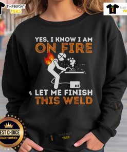 Metal worker wearing 'Pretty Yes I Know I Am On Fire' sweatshirt while welding, showcasing craftsmanship and style.