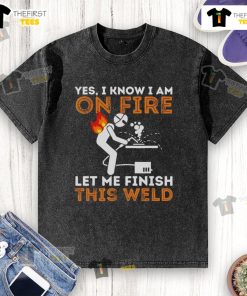 Metal worker in a 'Pretty Yes I Know I Am On Fire' t-shirt finishing a weld, showcasing welding skills and humor.