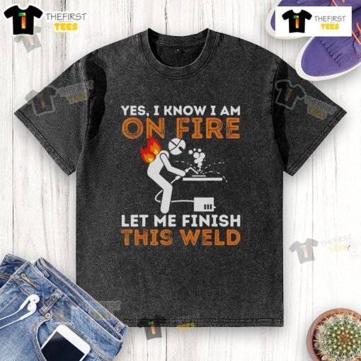 Metal worker in a 'Pretty Yes I Know I Am On Fire' t-shirt finishing a weld, showcasing welding skills and humor.