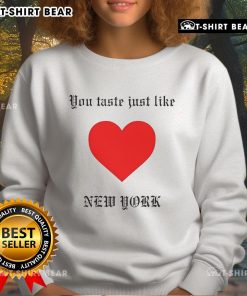 Cozy 'Top You Taste Just Like New York' sweatshirt displayed on a wooden table, perfect for casual city vibes.