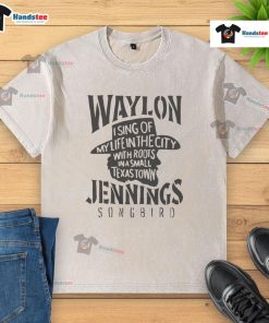 Waylon Jennings singing in a city, wearing a washed t-shirt that reflects his small Texas town roots.