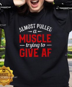 Funny sweatshirt design saying 'Almost Pulled A Muscle Trying To Give Af' with a playful illustration, perfect for humor lovers.