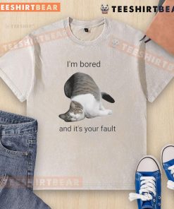 Alt Text: Funny cat looking bored in a washed t-shirt, playfully blaming its owner for the lack of fun activities.